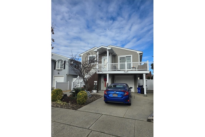 View of front of home with stairway, driveway, a balcony, and a garage