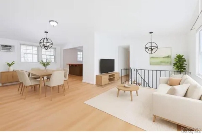 Living area featuring a chandelier, light wood finished floors, and an AC wall unit