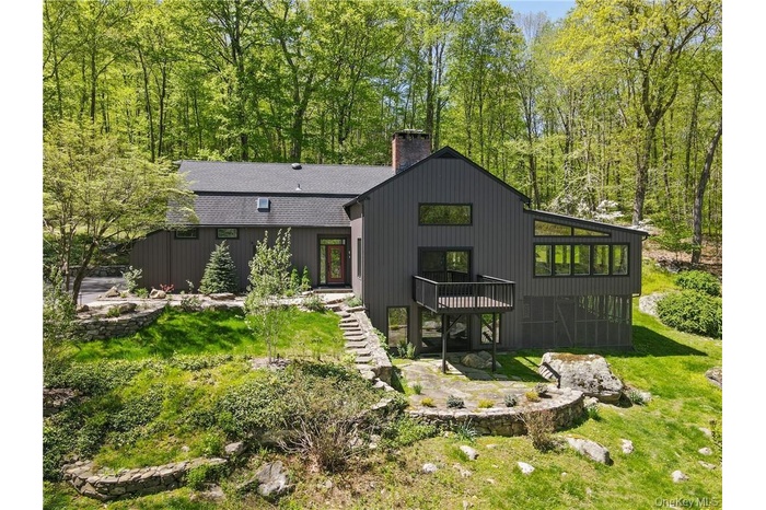 Rear view of property with a patio area, a chimney, a yard, and roof with shingles