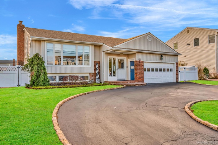 View of front of home featuring brick siding, driveway, a shingled roof, a chimney, and a garage