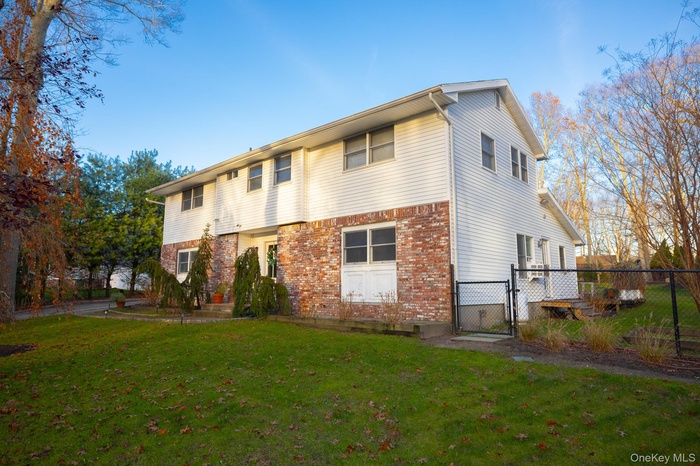 Rear view of property featuring a gate and brick siding