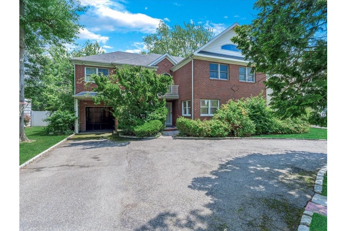 View of front of home with driveway, brick siding, and a balcony