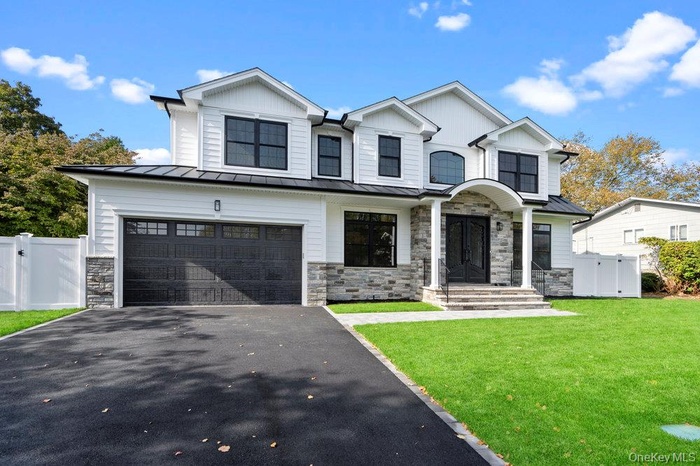View of front of property with stone siding, a gate, asphalt driveway, a standing seam roof, and a metal roof