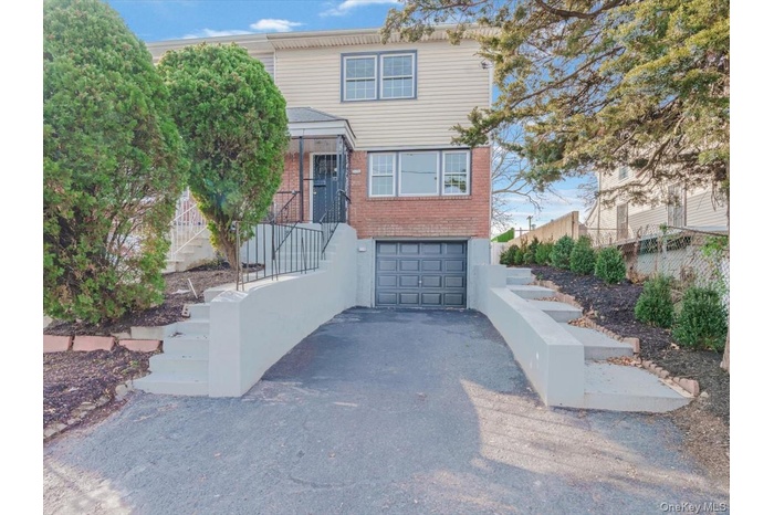 View of front of home with brick siding, asphalt driveway, and an attached garage