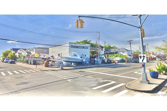 View of asphalt street featuring traffic signs, curbs, sidewalks, and street lighting
