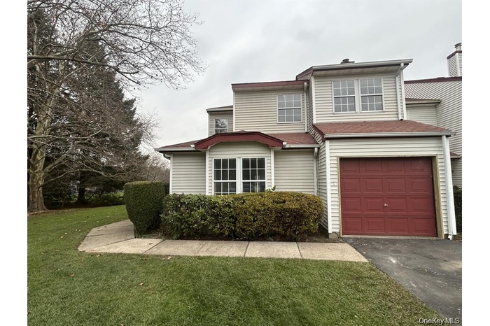 Traditional-style house with a front yard, an attached garage, and asphalt driveway