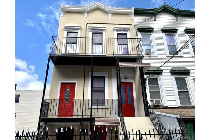 Townhome / multi-family property featuring a balcony, a fenced front yard, and stucco siding