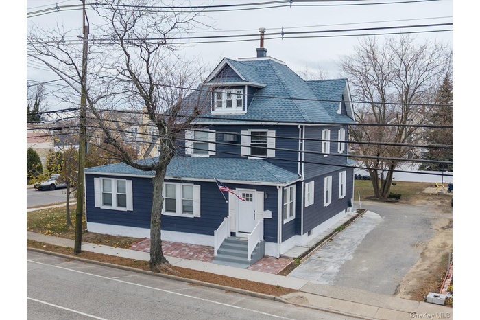 Traditional style home with roof with shingles, a chimney, entry steps, and driveway