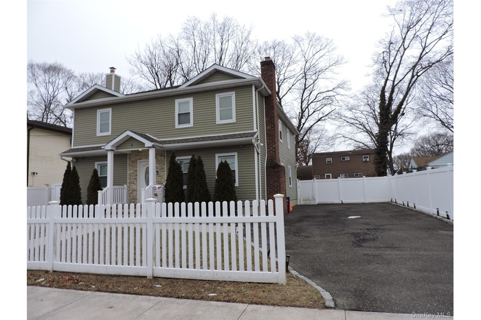 View of front of house featuring a chimney, a fenced front yard, and driveway