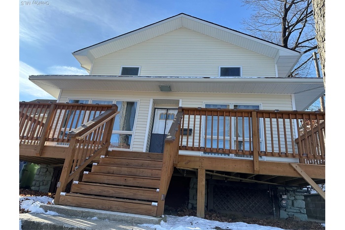 Snow covered house featuring a wooden deck and stairs