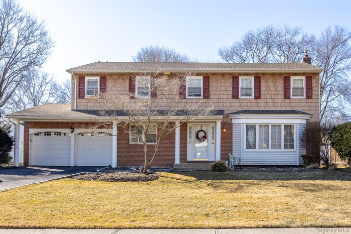 View of front of property with driveway, a chimney, roof with shingles, an attached garage, and a front yard