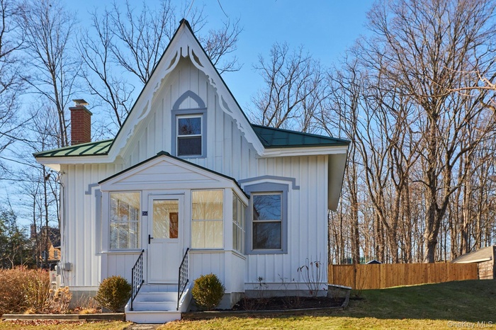 View of front facade with board and batten siding, a chimney, and a metal roof