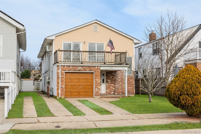 Traditional-style house with brick siding, a balcony, and a garage