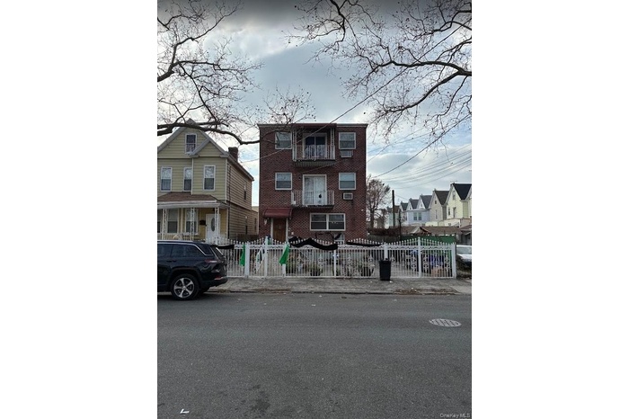 View of front of property featuring brick siding, a fenced front yard, and a residential view