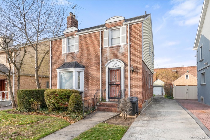 View of front of home with brick siding, a chimney, and a gate