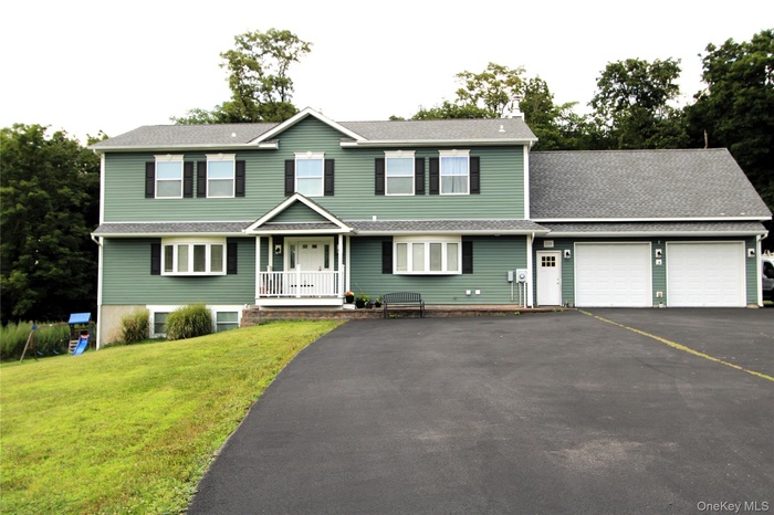 View of front facade with asphalt driveway, an attached garage, a front yard, and roof with shingles