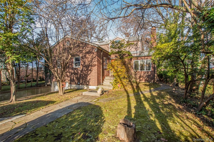 View of front of property featuring brick siding, a chimney, and a front lawn