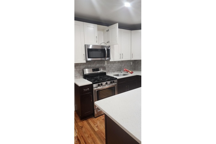 Kitchen featuring stainless steel stove, white cabinets, light stone countertops, and decorative backsplash