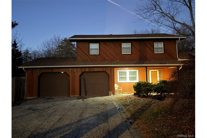 View of front of home with driveway and a shingled roof