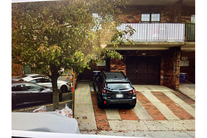 View of front facade featuring brick siding, driveway, and a garage