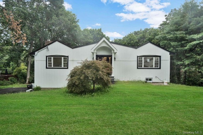 View of front of home with a front lawn, a chimney, and view of scattered trees