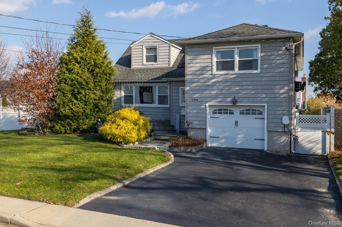 View of front of home with roof with shingles, an attached garage, asphalt driveway, and a gate