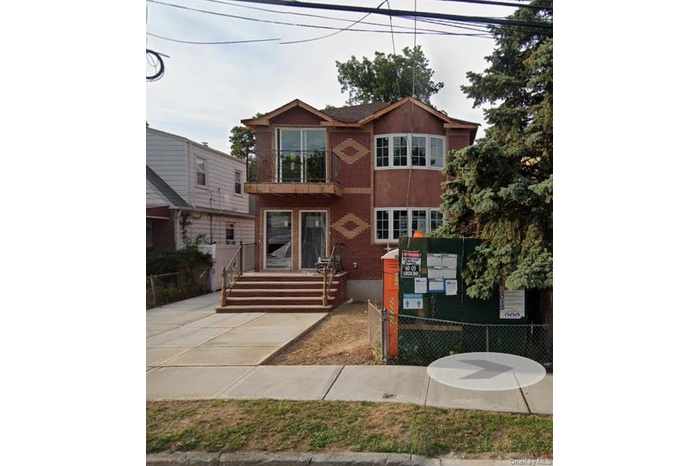 View of front of house featuring a balcony and brick siding