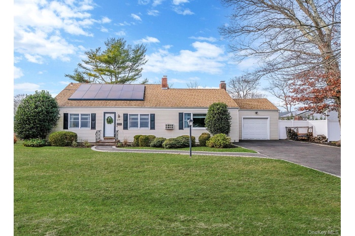 Ranch-style home with driveway, roof mounted solar panels, a chimney, and roof with shingles