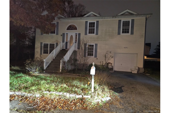 Bi-level home featuring an attached garage and asphalt driveway