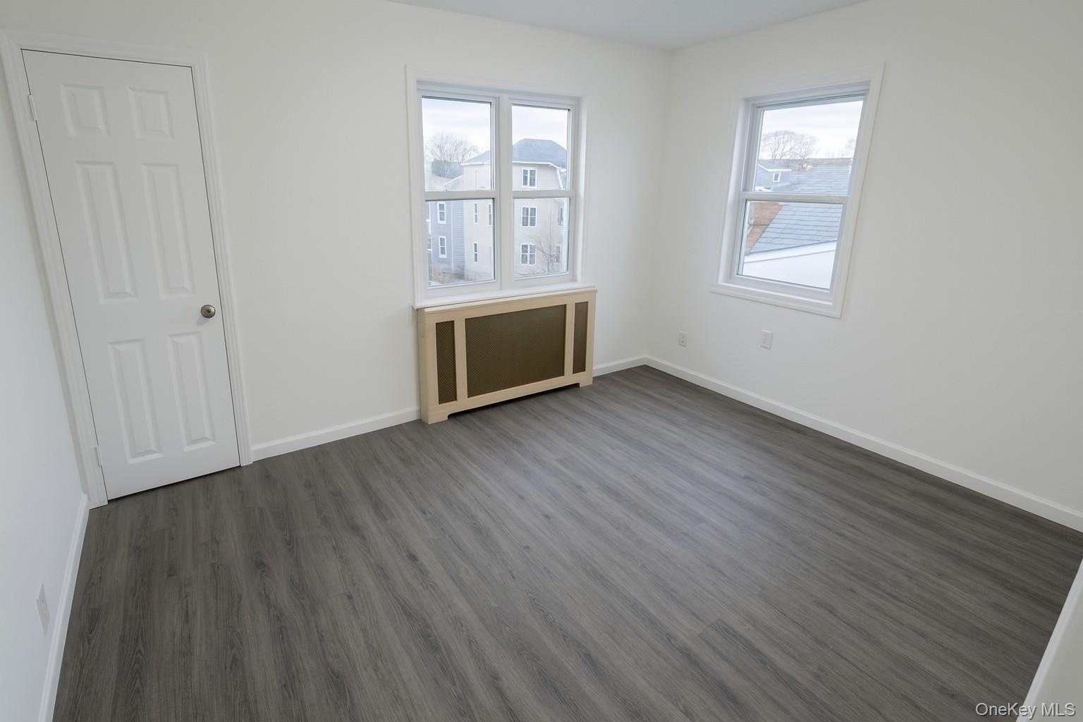 Unfurnished bedroom featuring radiator heating unit and wood finished floors