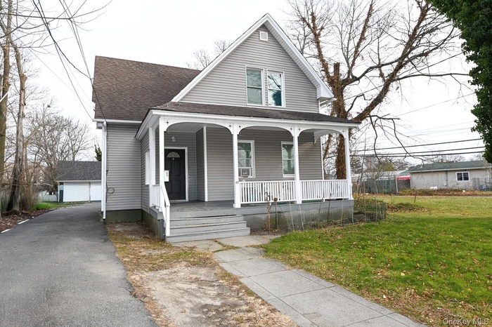 View of front of house with a front lawn, covered porch, and roof with shingles