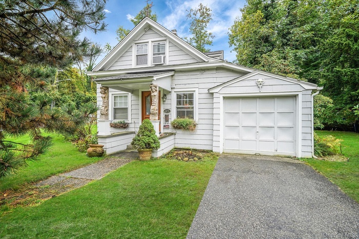 View of front of house with a front lawn, driveway, a garage, and a porch