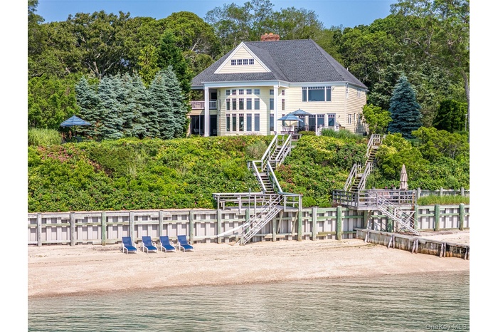 View of front facade with stairway, a chimney, and a water view