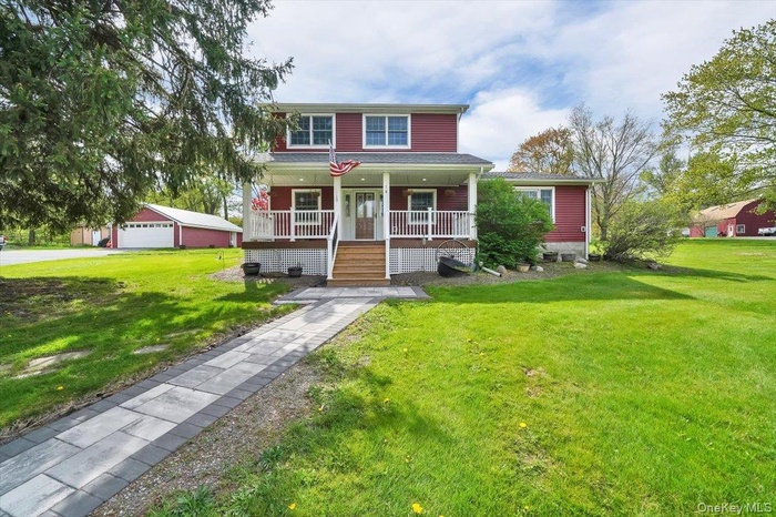 View of front of home with a porch, a front yard, and a garage