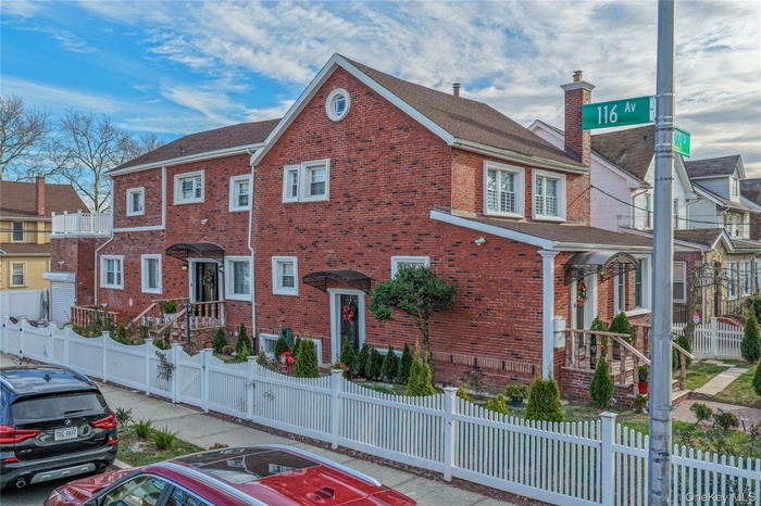 View of front of property featuring a fenced front yard, brick siding, a chimney, and a shingled roof