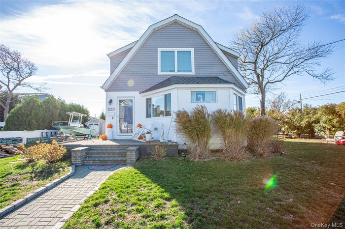 Shingle-style home featuring a front yard, a gambrel roof, and roof with shingles