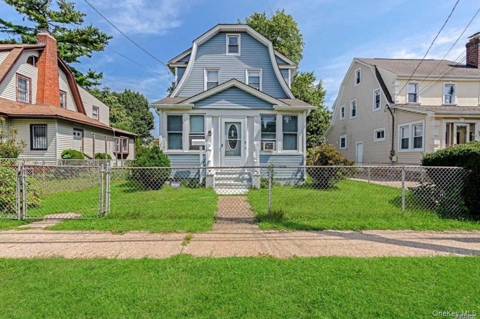 Dutch colonial with a gambrel roof, a fenced front yard, and a gate