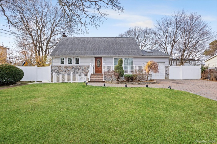 View of front of property with a chimney, stone siding, decorative driveway, an attached garage, and roof with shingles
