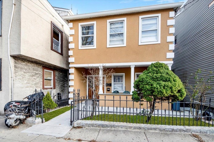 View of front of home featuring covered porch, a fenced front yard, stucco siding, and a gate