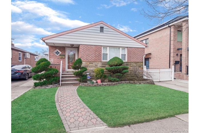 View of front of home featuring a front yard, stone siding, and brick siding