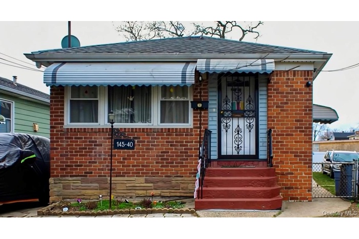 View of front facade featuring a shingled roof and brick siding