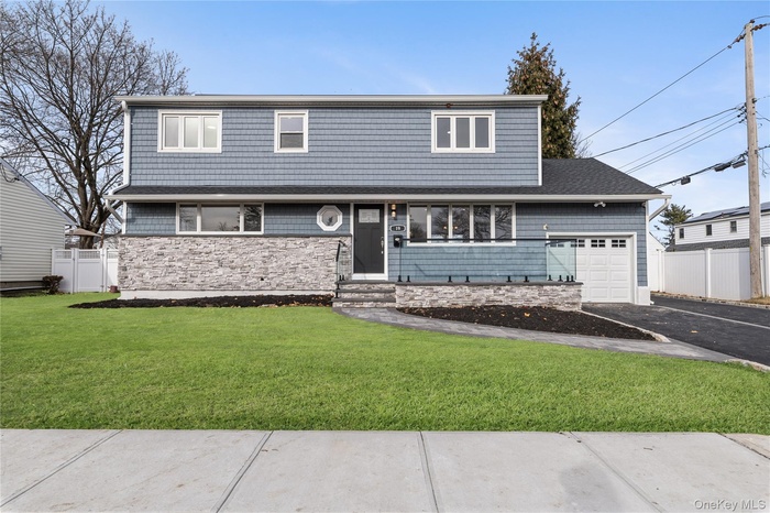View of front facade featuring asphalt driveway, stone siding, and a garage
