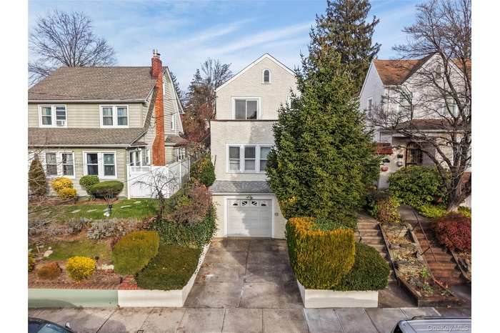 View of front of home with driveway, a chimney, a garage, and a shingled roof