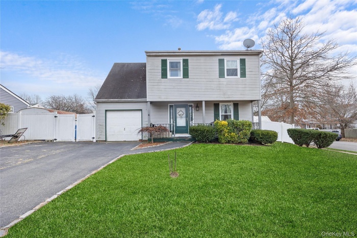 Colonial inspired home with driveway, a gate, and a garage
