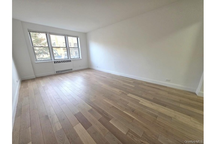 Unfurnished room with light wood-style floors and radiator heating unit