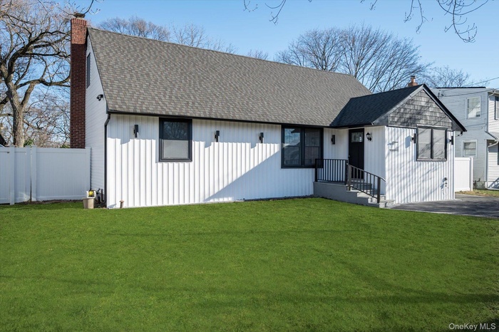 View of front of home with a chimney and a shingled roof