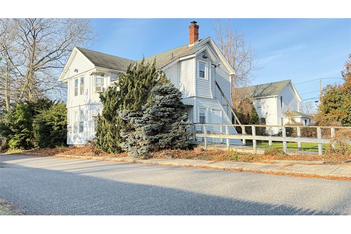 View of side of property featuring a chimney and a fenced front yard