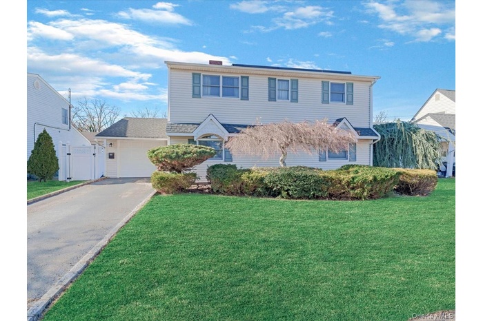 Traditional-style house featuring a front yard, asphalt driveway, and a gate