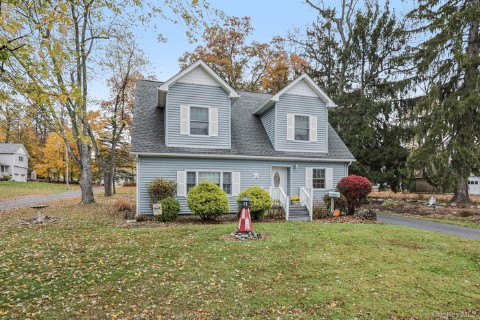 View of front facade with a front lawn and a shingled roof