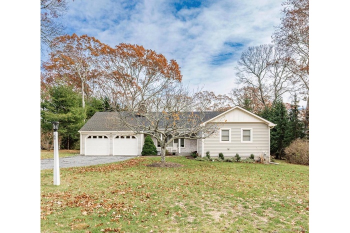 Ranch-style house with board and batten siding, a front yard, asphalt driveway, a garage, and a shingled roof